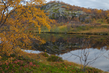 Autumn landscape. The rocks and the sky are reflected in the lake.