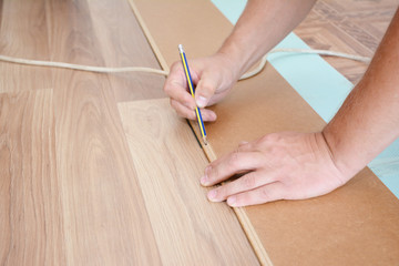 Contractor laying wooden laminate flooring. Laminate flooring installation.