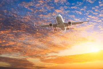 Fototapeta premium Airplane flying above dramatic clouds during sunset