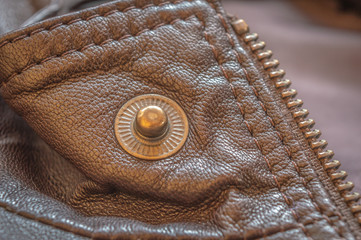 Collar button and zip of an elegant tan and brown leather jacket