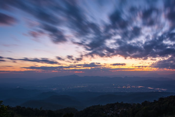 Fototapeta premium Colorfull sunset twilight sky with cloud flow over small town's light.