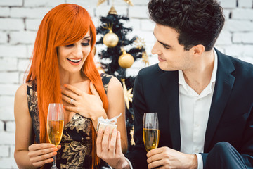 Man giving his wife present for Christmas, both drink sparkling wine