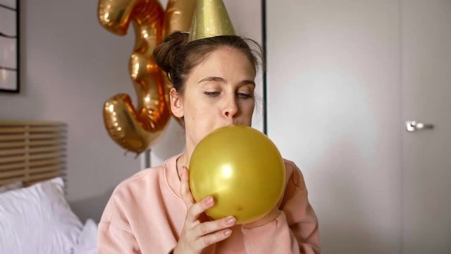 Birthday girl blowing a gold balloon