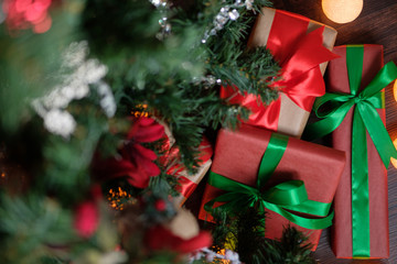 Gifts lie under the tree with a glowing gerland on a dark wooden floor