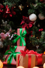 Gifts lie under the tree with a glowing gerland on a dark wooden floor