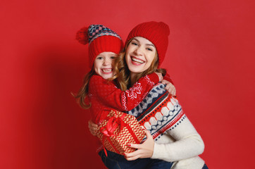 happy family mother and child daughter with christmas gifts on red background