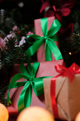 Gifts lie under the tree with a glowing gerland on a dark wooden floor