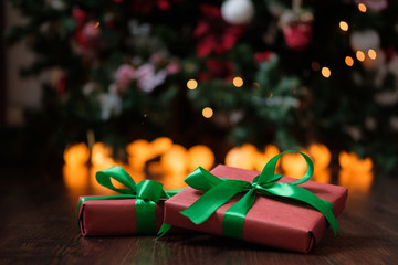 Gifts lie under the tree with a glowing gerland on a dark wooden floor