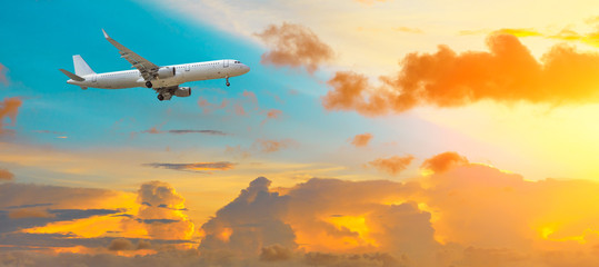 Airplane flying above dramatic clouds during sunset
