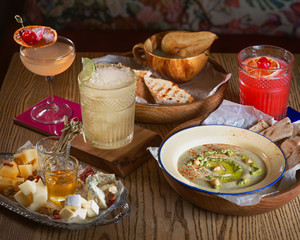 Food: hummus, jelly, different type of cheese and alcohol cocktails on the table