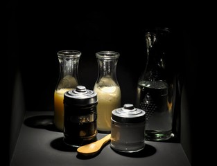 Kitchen simple still life concept with glass bottles ingredients isolated on black background.