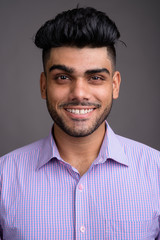Obraz premium Young handsome Indian businessman against gray background