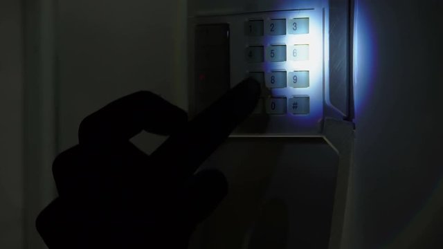 Burglar with flashlight trying to disarm security alarm system, housebreaking