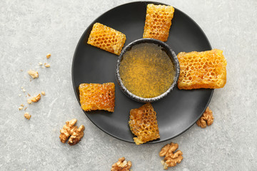 Bowl with honey and sweet honeycombs on plate