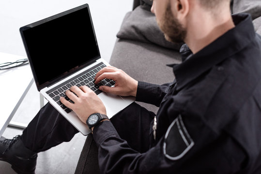 Cropped View Of Police Officer Sitting On Couch And Typing On Laptop Keyboard