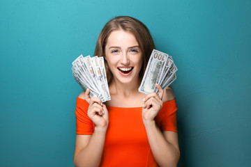 Happy young woman with a lot of money on color background
