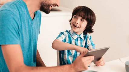 Happy Young Father and Son Using Tablet at Home.