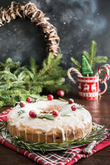 Traditional homemade Christmas cake with garnish cranberry and rosemary on decorative plate.