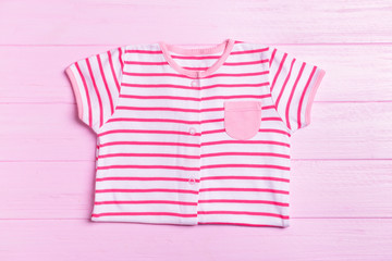 Baby clothes on color wooden background, top view