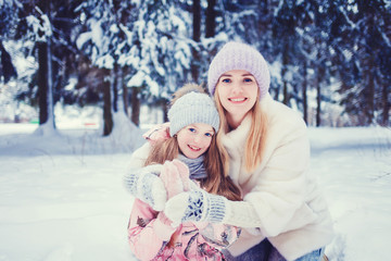 happy family mother and child daughter playing and hugging on a winter walk. christmas