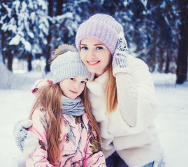 close-up portrait of mom and daughters hugging in winter park