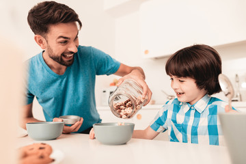 Smiling Son and Father Have Breakfast in Kitchen.