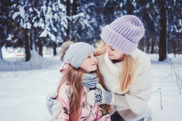 Mother and child girl having fun, playing and laughing on snowy winter walk in nature.