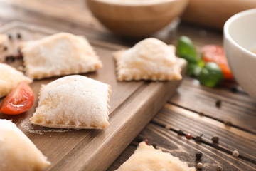 Board with uncooked ravioli on wooden table