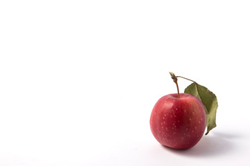 Small apple with green leaf on white background. ranetka