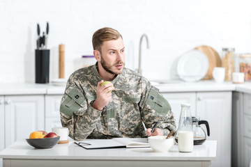 army soldier sitting at kitchen table and eating apple