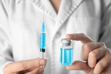 Doctor holding syringe and ampule, closeup