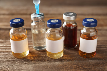Different ampules with syringe on wooden table