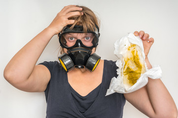 Mother with gas mask changing smelly diaper