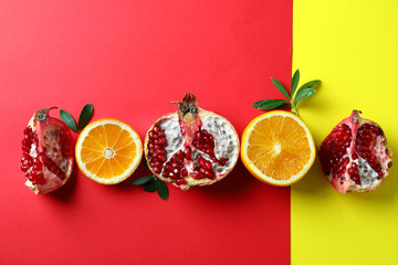 Tasty fresh pomegranates and oranges on color background, flat lay