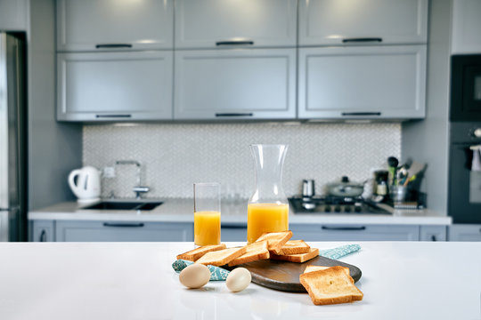 Portion of toasts on a wooden board with orange juice. Breakfast is served on a table with light blue napkin.