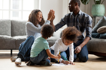 Happy African American family playing together indoors, adorable toddler son and littler...