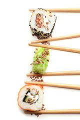 Tasty sushi rolls with chopsticks on white background