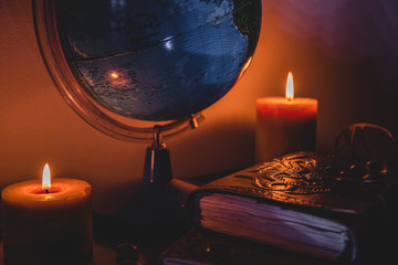globe in candles light background on a wooden surface with stones and ancient books