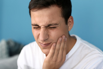 Fototapeta premium Young man suffering from toothache at home