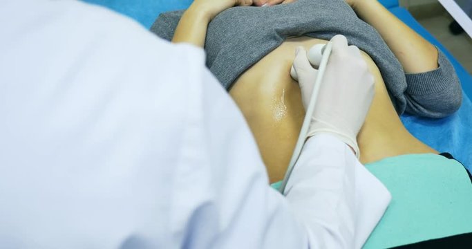 Doctor making a ultrasound diagnostic of stomach. Looking to thin abdomen of young women at ultrasound device screen on the hospital