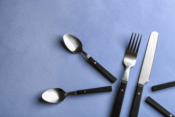 Spoons, fork and knife on color background