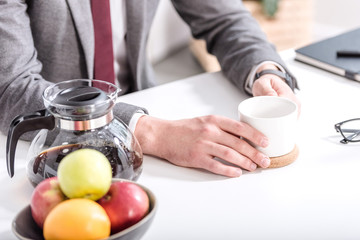 Fototapeta na wymiar cropped view of businessman drinking coffee in kitchen