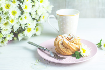 Delicious cake with coconut chips on pink plate on white table, autumn white chrysanthemum and cup of coffee