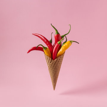 Hot Chili pepper in ice cream cone on pink background. Minimal food concept.