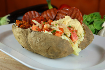 Kumpir - Traditional Turkish meal with baked potato, butter, cheese, bulgur salad, beef sausage and hot spices