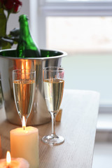 Glasses of champagne with burning candles on wooden table