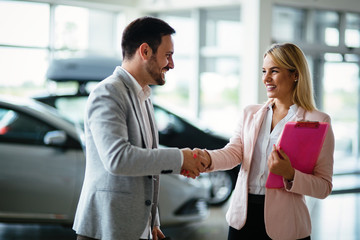 Young female car sales consultant working in showroom