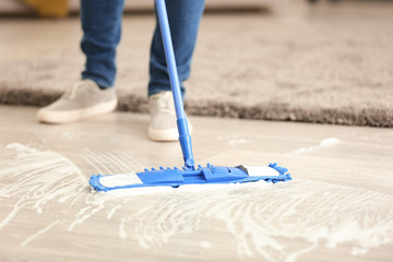 Young man cleaning floor in his flat