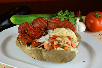 Kumpir - Traditional Turkish meal with baked potato, butter, cheese, bulgur salad, beef sausage and hot spices