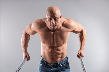 Muscular bodybuilder training on grey background